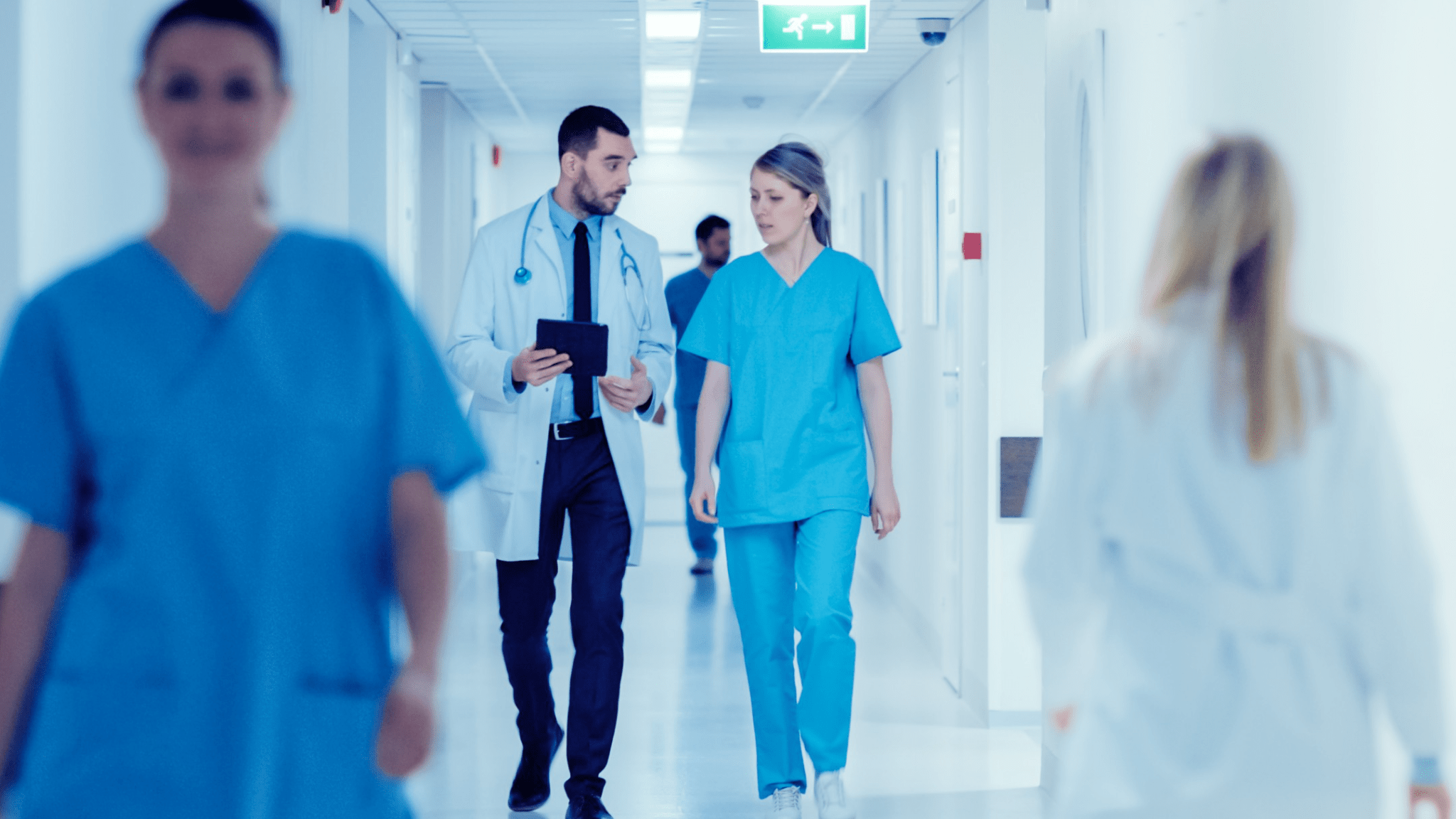 Doctor and Nurse speaking while walking down the hall of a hospital